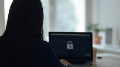 An image of a woman working in front of a laptop with the screen showing a lock icon.