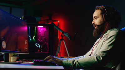 A man playing video game on a gaming PC in dark room