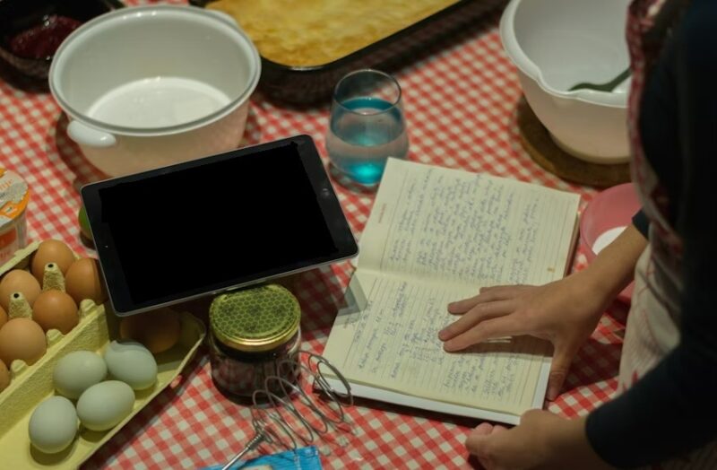 Woman reading recipes next to her tablet.